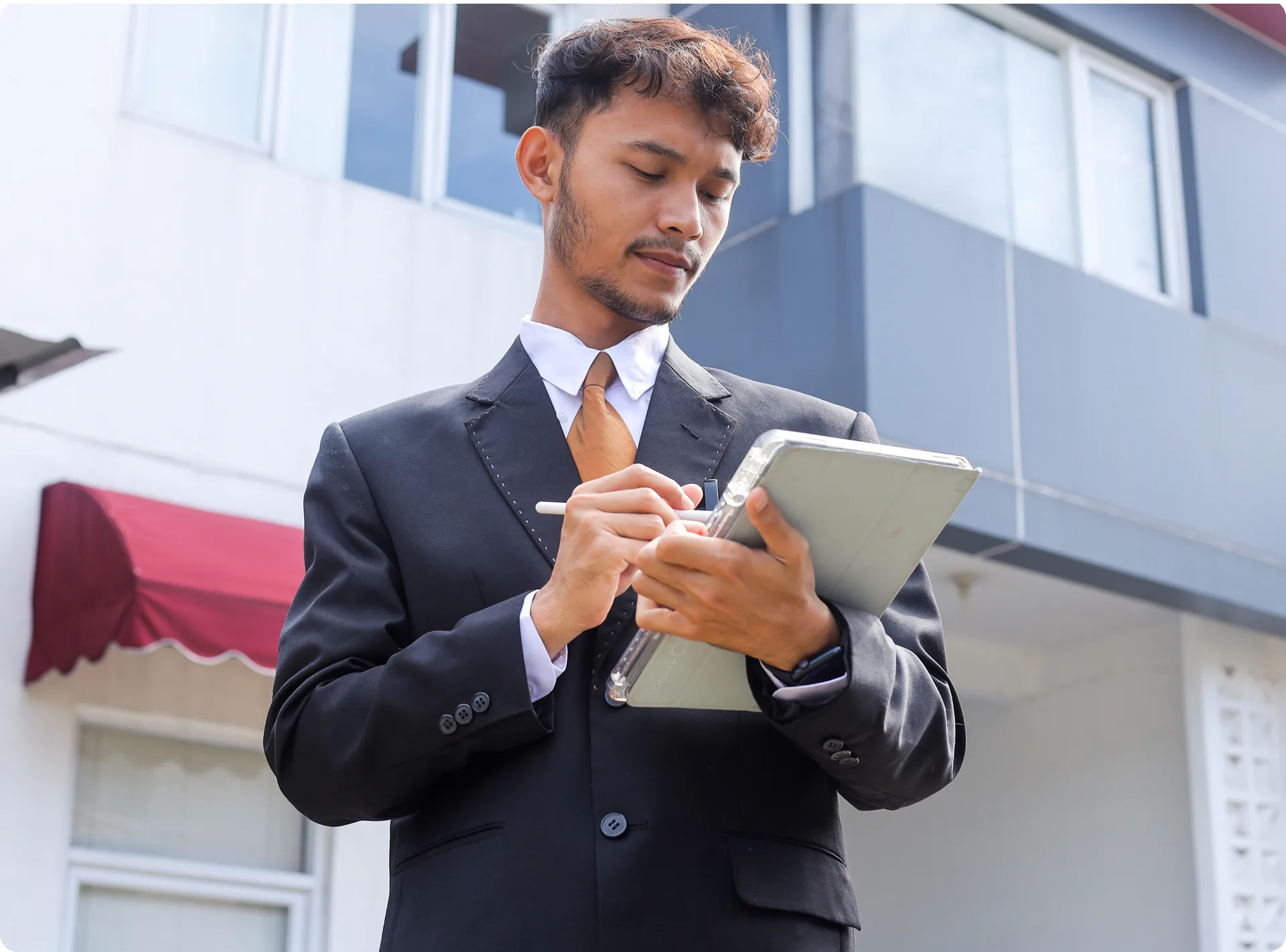 A property manager taking notes on a tablet outside a building