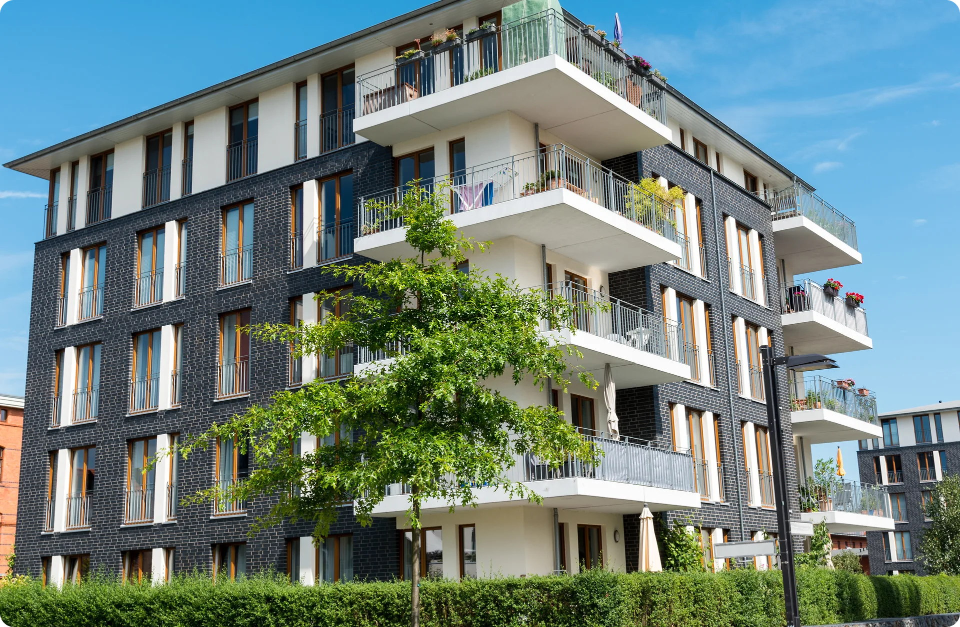 A modern apartment building with planted balconies on a clear day