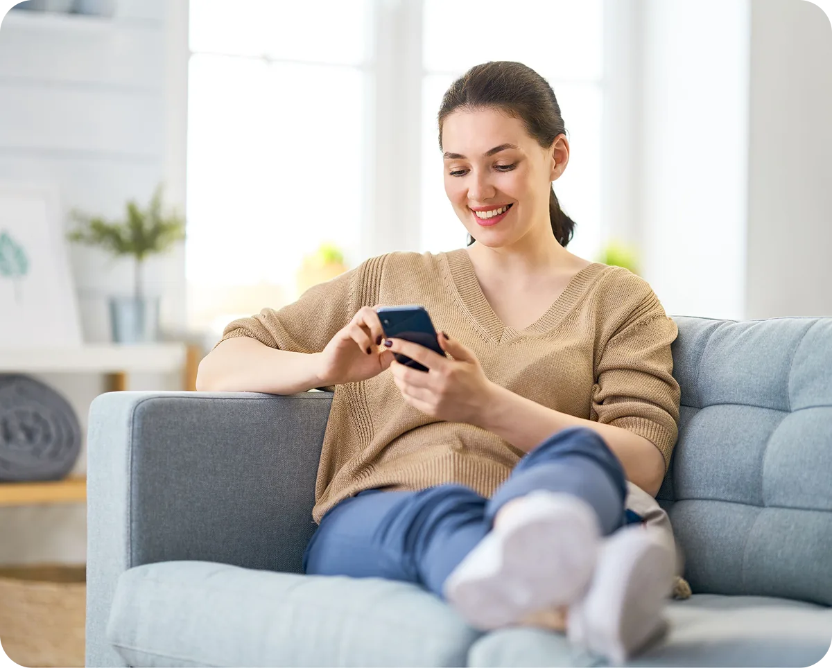 A resident relaxing on a sofa with a phone