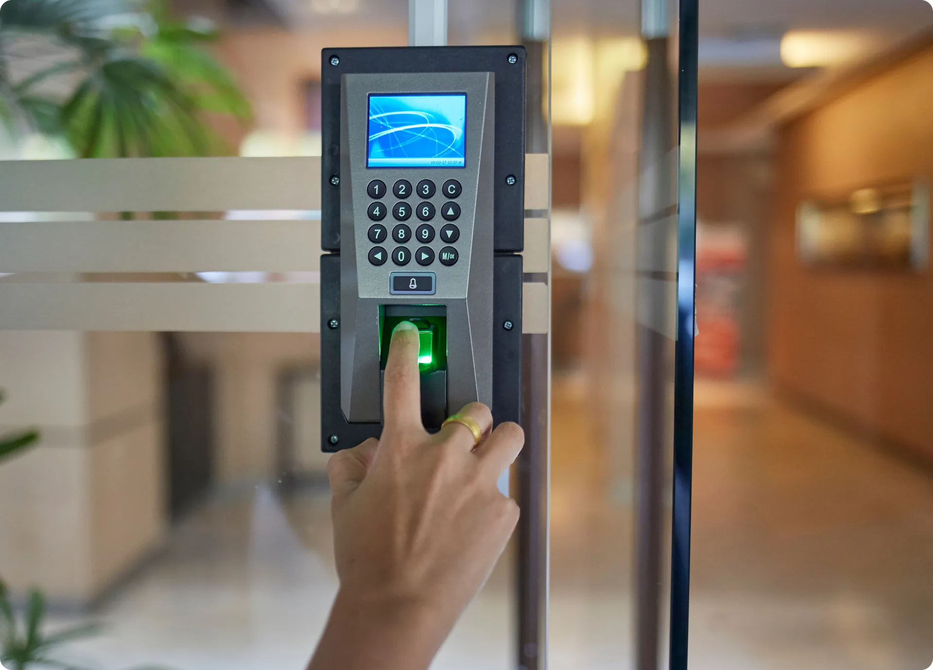 A hand using a fingerprint reader on a building access panel