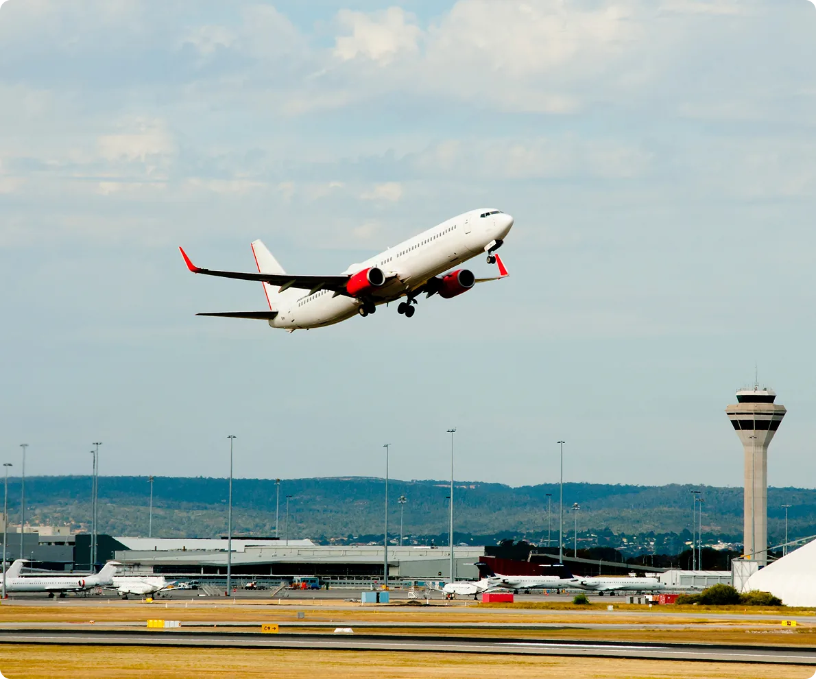 An aircraft taking off past an airport control tower