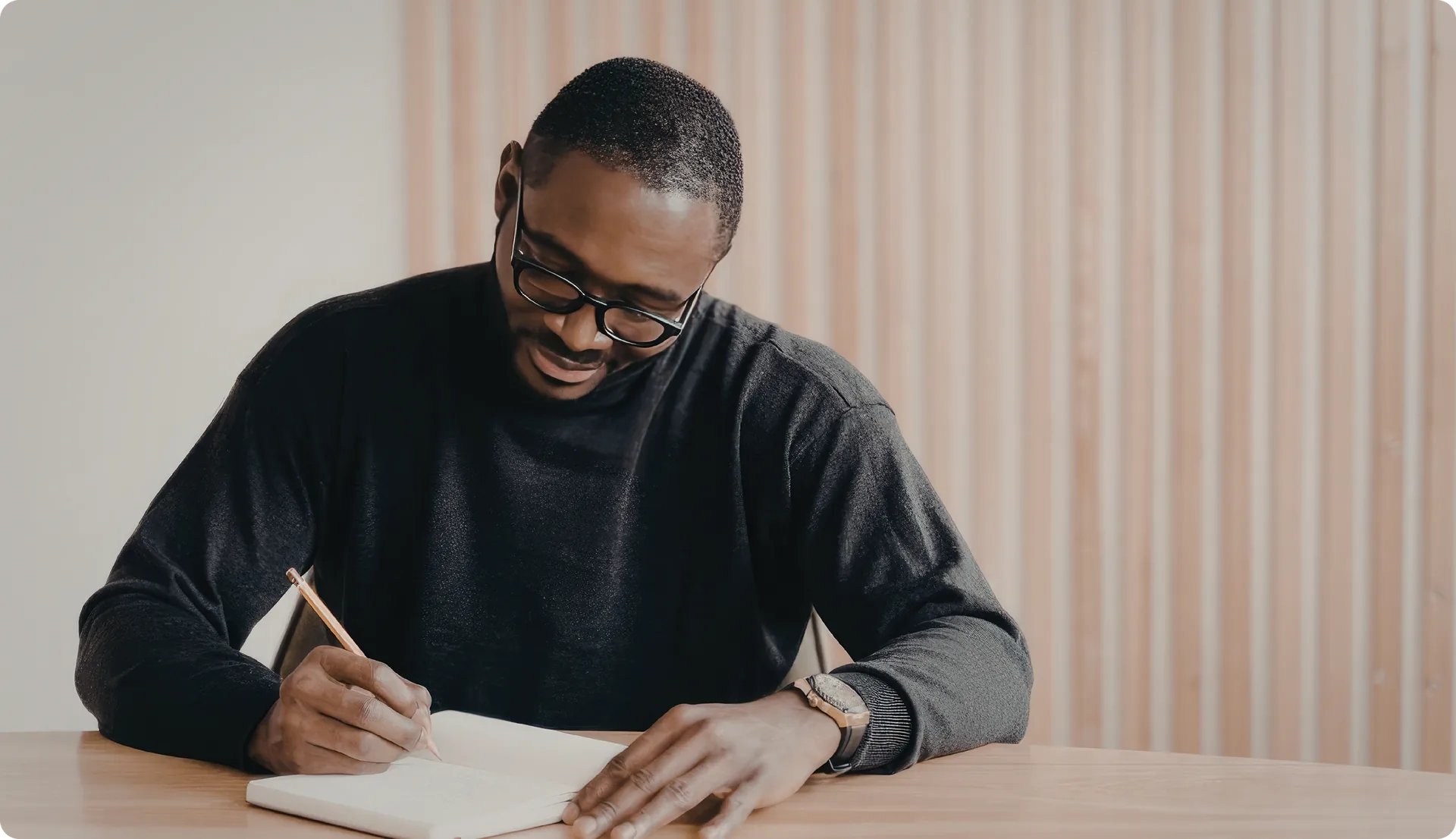 A person writing notes in a notebook at a desk