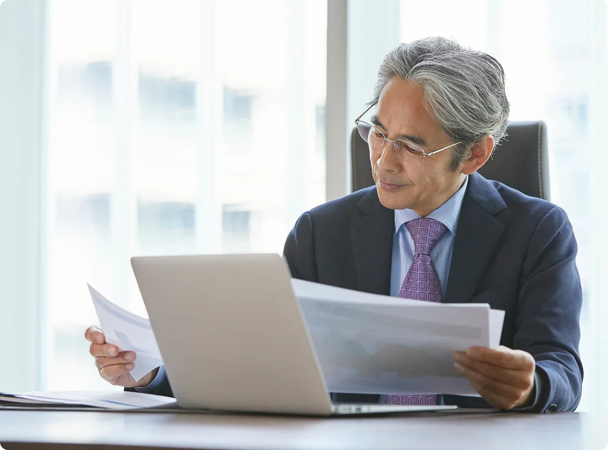 A portfolio manager reviewing documents at a laptop